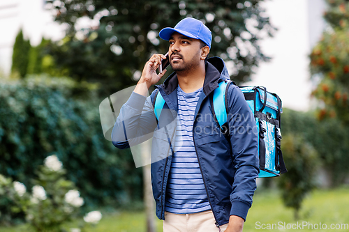 Image of indian delivery man with bag calling on smartphone