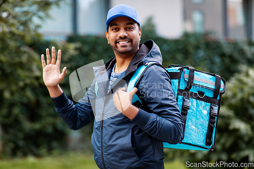 Image of happy smiling indian delivery man with bag in city