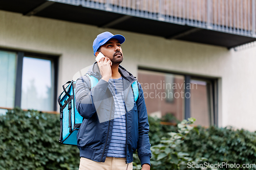 Image of indian delivery man with bag calling on smartphone