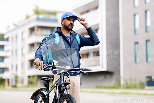 Image of indian delivery man with bag and bicycle in city