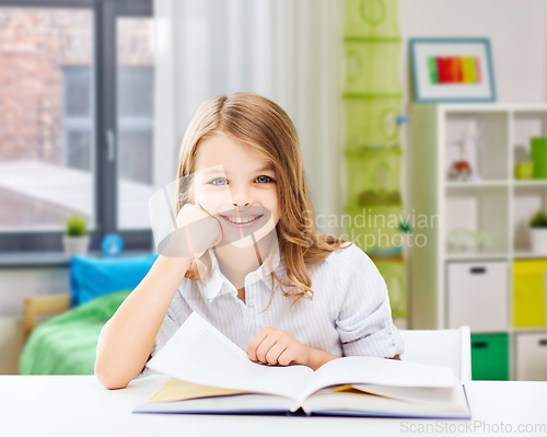 Image of happy smiling student girl reading book at home
