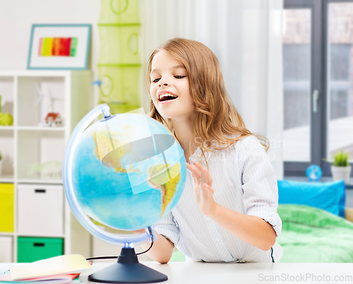 Image of smiling student girl with globe at home