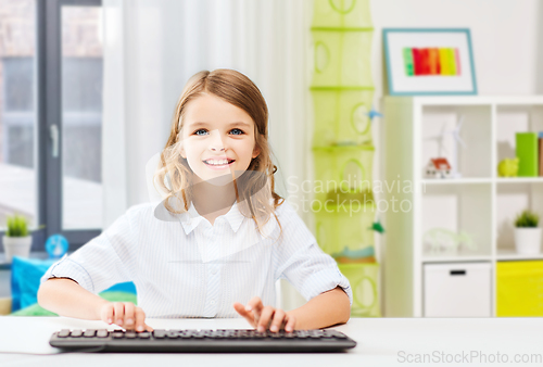 Image of happy student girl with keyboard at home