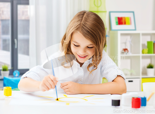 Image of happy girl with brush and colors drawing at home