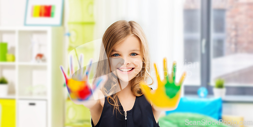 Image of smiling girl showing painted hands at home