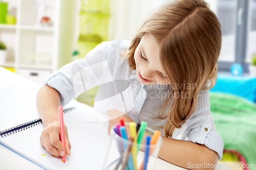 Image of girl with felt-tip pen drawing picture in notebook