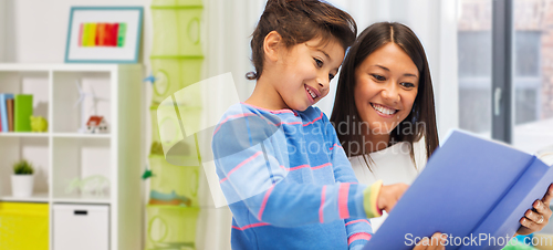 Image of happy mother and daughter reading book at home