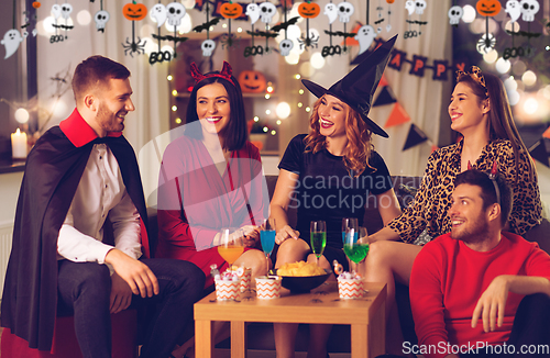 Image of happy friends in halloween costumes at home party