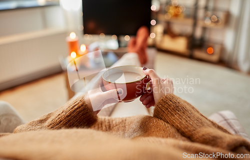 Image of hands of woman drinking hot chocolate at home