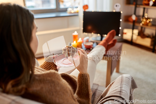Image of woman watching tv and eating waffle on halloween