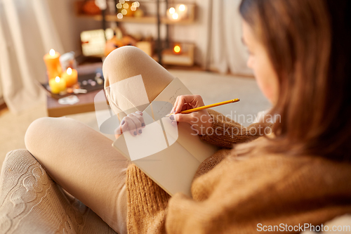 Image of woman writing to diary at home on halloween