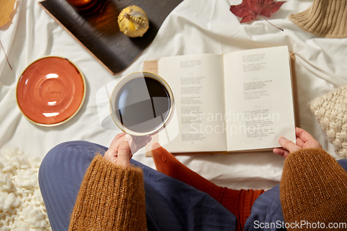 Image of woman drinking coffee and reading book in autumn