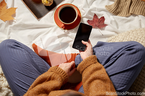 Image of woman with smartphone at home in autumn