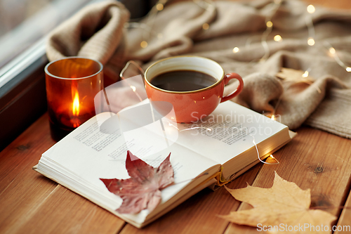 Image of cup of coffee, book on window sill in autumn