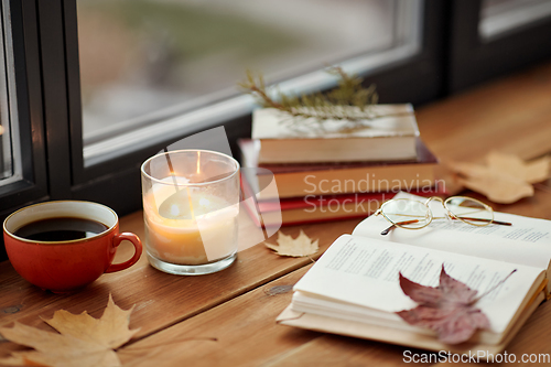 Image of book, coffee and candle on window sill in autumn