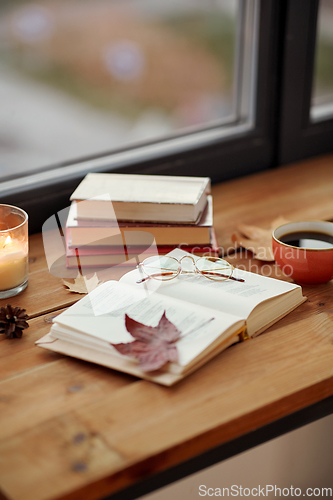 Image of book, coffee and candle on window sill in autumn