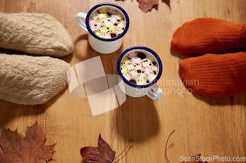 Image of couple of feet in socks, coffee and autumn leaves