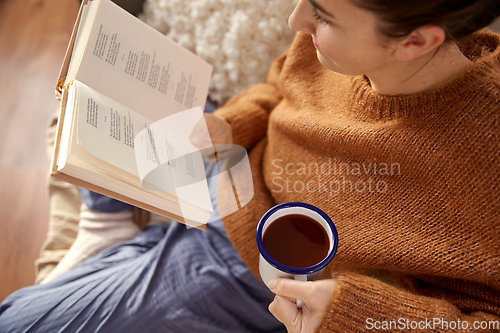 Image of woman reading book and drinking coffee at home