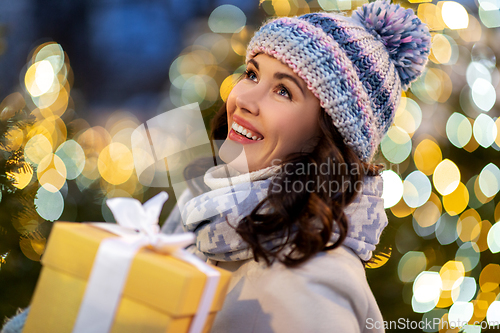 Image of happy woman with christmas gift over lights