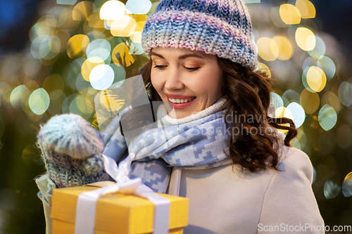 Image of happy woman with christmas gift over lights