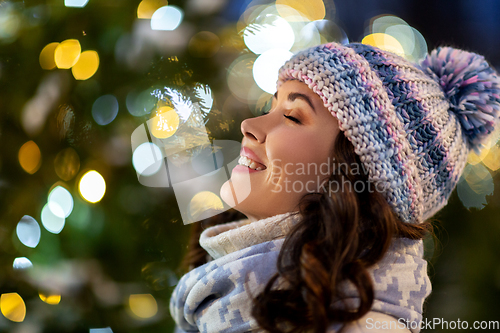 Image of portrait of happy young woman in christmas lights