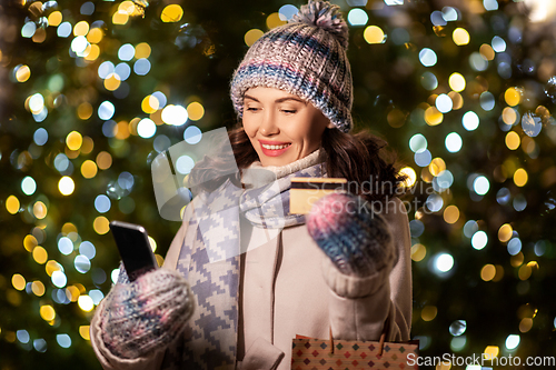 Image of woman with phone, credit card and christmas gifts