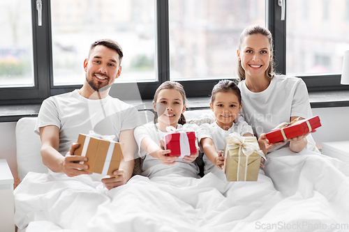 Image of happy family with christmas gifts in bed at home