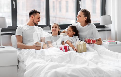 Image of happy family with christmas gifts in bed at home