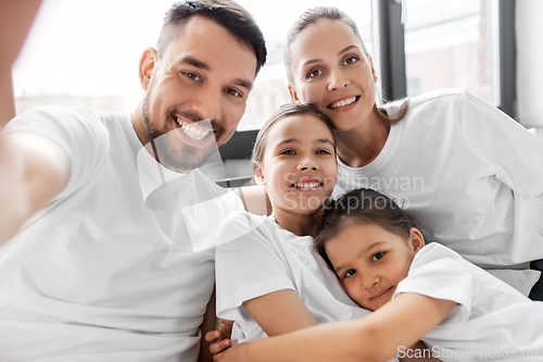 Image of happy family taking selfie in bed at home