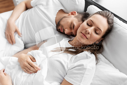 Image of happy couple sleeping in bed at home