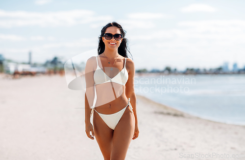 Image of smiling young woman in bikini swimsuit on beach