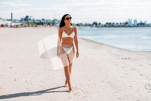 Image of smiling young woman in bikini swimsuit on beach