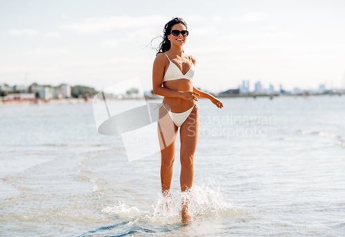 Image of smiling young woman in bikini swimsuit on beach