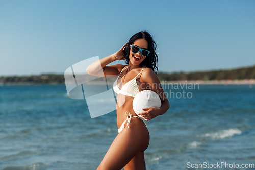 Image of woman in bikini posing with volleyball on beach