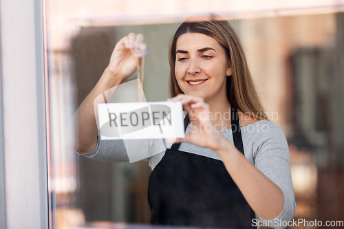 Image of happy woman hanging reopen banner to door glass