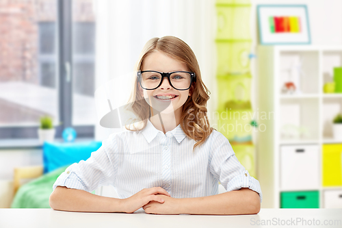 Image of smiling student girl in glasses sitting at table
