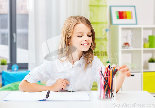 Image of happy girl drawing with pencils at home