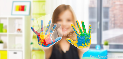 Image of smiling girl showing painted hands at home