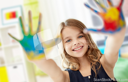 Image of smiling girl showing painted hands at home