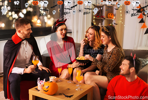 Image of happy friends in halloween costumes at home party