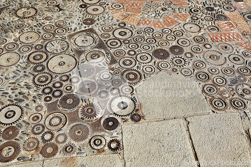 Image of Unusual floor with pattern from pebbles, brick and rusty metal d