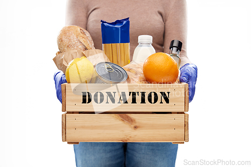 Image of woman in gloves with food donation in wooden box