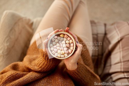 Image of woman holding mug of hot chocolate and marshmallow