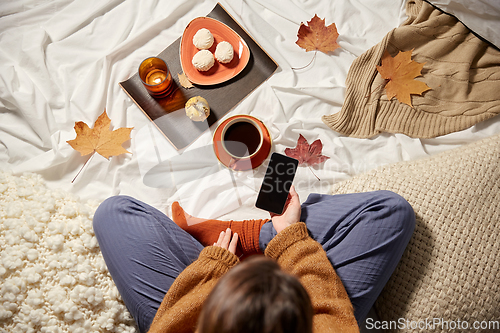 Image of woman with smartphone at home in autumn