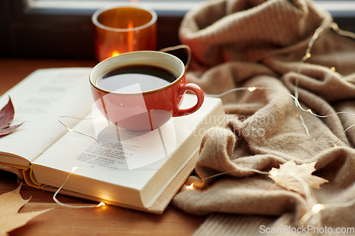 Image of cup of coffee, book on window sill in autumn