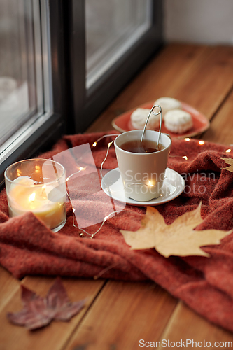 Image of cup of tea and candle on window sill in autumn