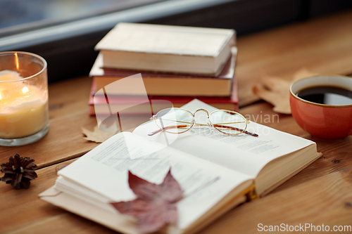 Image of book, coffee and candle on window sill in autumn