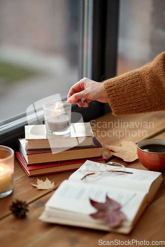 Image of hand with match lighting candle on window sill