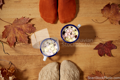 Image of couple of feet in socks, coffee and autumn leaves