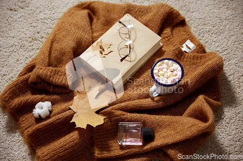 Image of cup of marshmallow, book and glasses on sweater